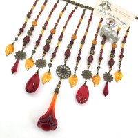 Adorn your personal space with our unique, exceptional chandelier beaded curtain or what we lovingly refer to as a "Window Necklace".  The fluid nature (similar to a necklace) of this eleven strand hanging, allows for gentle movement after being hung which creates wonderful and beautiful reflections with just about any light and atmosphere.

Vintage Murano chandelier focal, new and vintage chandelier prism, and stamped Strass Swarovski crystal. Beads: Ruby, Swarovski, and Czech glass beads.