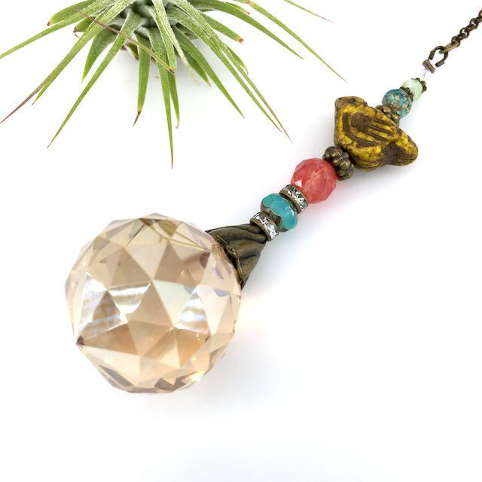 This charming handmade crystal sun catcher hanging will adorn any room with rainbows and bring lively reflections. Simple and elegant, our unique design features a high-quality Asfour Honey AB (30mm) faceted crystal prism sphere, meticulously hand-strung with unique beads. Czech Glass bird focal, vintage Czech Glass beads and Cherry Quartz gemstone. It is completed with chain and hook, ensuring effortless hanging and allowing gentle movement that makes the rainbows dance. Hanging Length of 17".