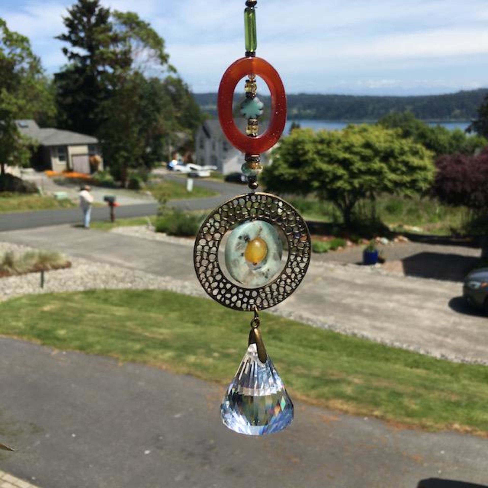 With a nod to natural tones and textures, this one of a kind large crystal sun catcher hanging, holds a gorgeous shape and design featuring a 40mm faceted crystal prism (epic rainbow maker)with unique gemstones.Simplistic in our unique and handmade design with a large crystal prism, carefully hand strung with various shaped gemstones; including Sardonyx Agate, Kiwi Sesame Jasper, and Carnelian. New and vintage Czech glass, and bronze beads for a refined appearance.  Epic Rainbow maker.