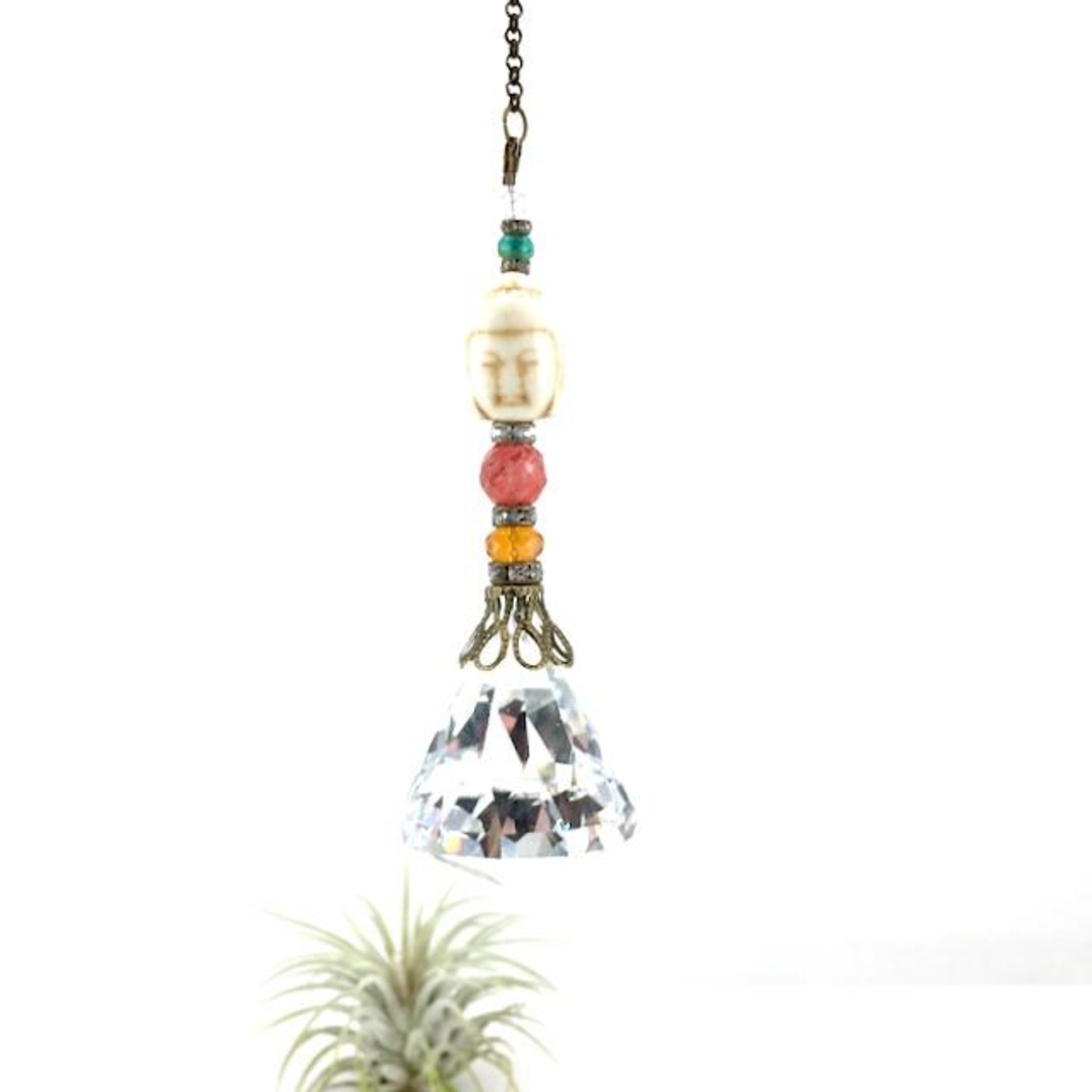 This charming handmade crystal hanging will adorn any room with rainbows and lively reflections, making it a delightful addition for yourself or a thoughtful gift that will be treasured.Featuring a high-quality, medium (40mm) faceted crystal prism, meticulously hand-strung with Howlite gemstone Buddha Focal, Cherry Quartz and distinctive Czech glass beads. It is completed with chain and hook, ensuring effortless hanging and allowing gentle movement that makes the rainbows dance.