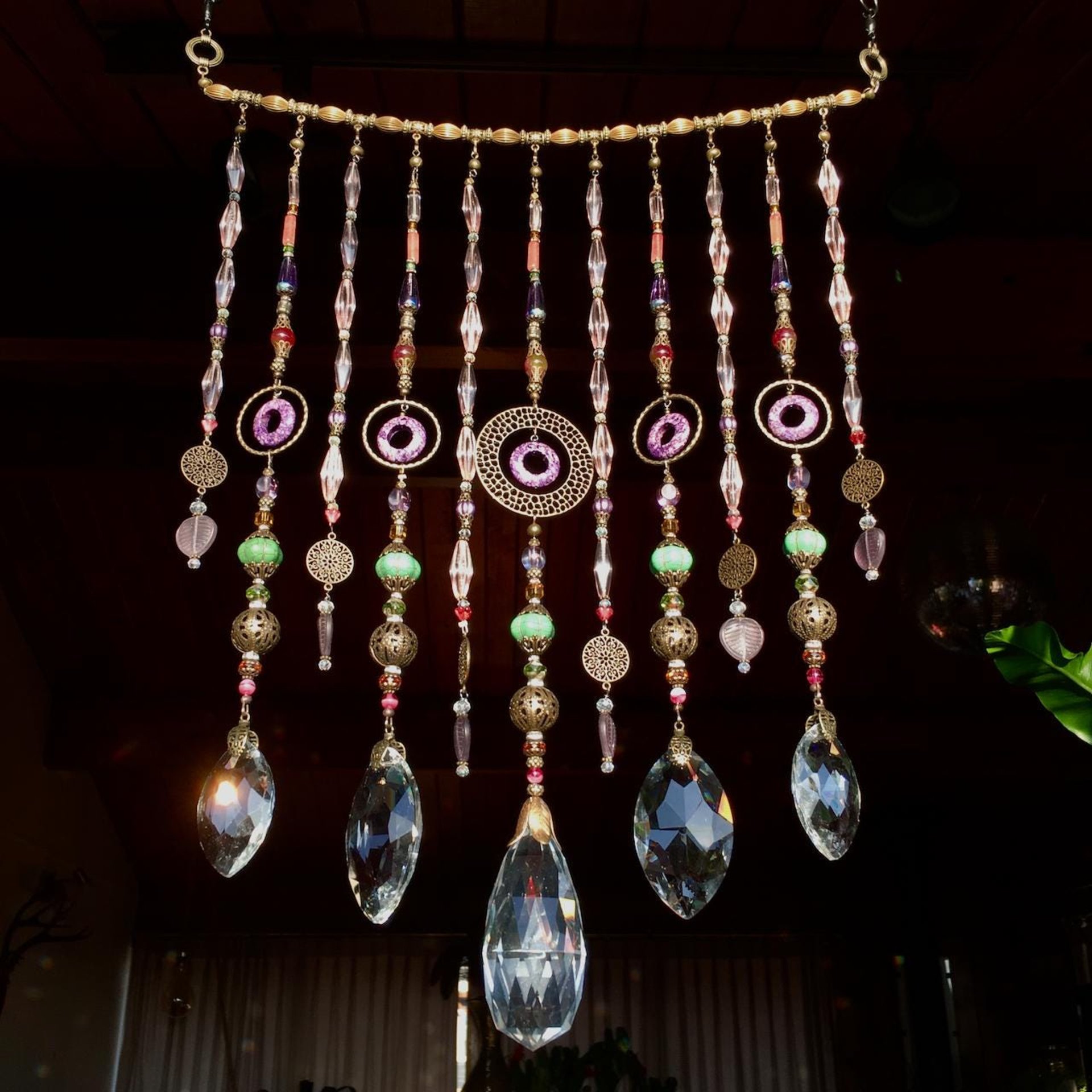 Adorn your personal space with our unique, exceptional chandelier beaded curtain or what we lovingly refer to as a "Window Necklace".  The fluid nature (similar to a necklace) of this eleven strand hanging, allows for gentle movement after being hung which creates wonderful and beautiful reflections with just about any light and atmosphere.Chandelier crystal prisms, creating epic rainbows! Gemstones and Crystal include: Malaysian Jade, Howlite, Purple Lace Agate, vintage and new Czech glass.