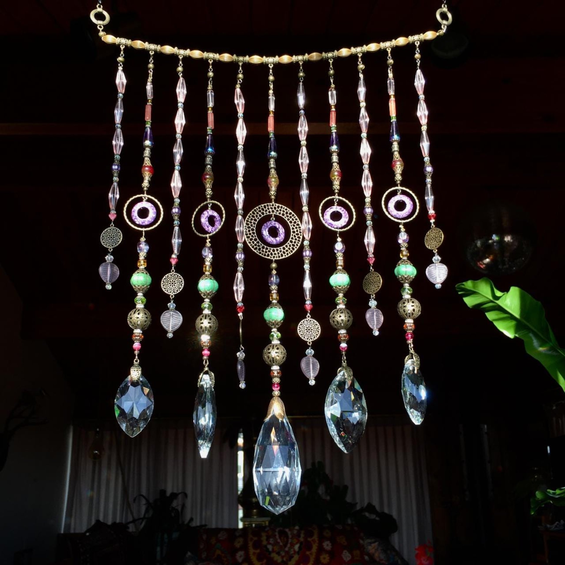 Adorn your personal space with our unique, exceptional chandelier beaded curtain or what we lovingly refer to as a "Window Necklace".  The fluid nature (similar to a necklace) of this eleven strand hanging, allows for gentle movement after being hung which creates wonderful and beautiful reflections with just about any light and atmosphere.Chandelier crystal prisms, creating epic rainbows! Gemstones and Crystal include: Malaysian Jade, Howlite, Purple Lace Agate, vintage and new Czech glass.