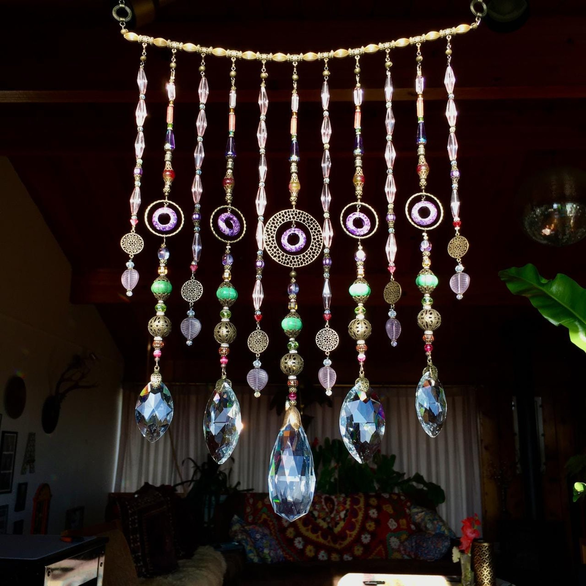 Adorn your personal space with our unique, exceptional chandelier beaded curtain or what we lovingly refer to as a "Window Necklace".  The fluid nature (similar to a necklace) of this eleven strand hanging, allows for gentle movement after being hung which creates wonderful and beautiful reflections with just about any light and atmosphere.Chandelier crystal prisms, creating epic rainbows! Gemstones and Crystal include: Malaysian Jade, Howlite, Purple Lace Agate, vintage and new Czech glass.