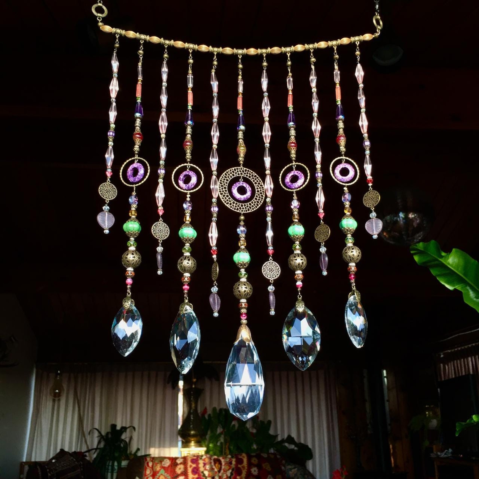 Adorn your personal space with our unique, exceptional chandelier beaded curtain or what we lovingly refer to as a "Window Necklace".  The fluid nature (similar to a necklace) of this eleven strand hanging, allows for gentle movement after being hung which creates wonderful and beautiful reflections with just about any light and atmosphere.Chandelier crystal prisms, creating epic rainbows! Gemstones and Crystal include: Malaysian Jade, Howlite, Purple Lace Agate, vintage and new Czech glass.